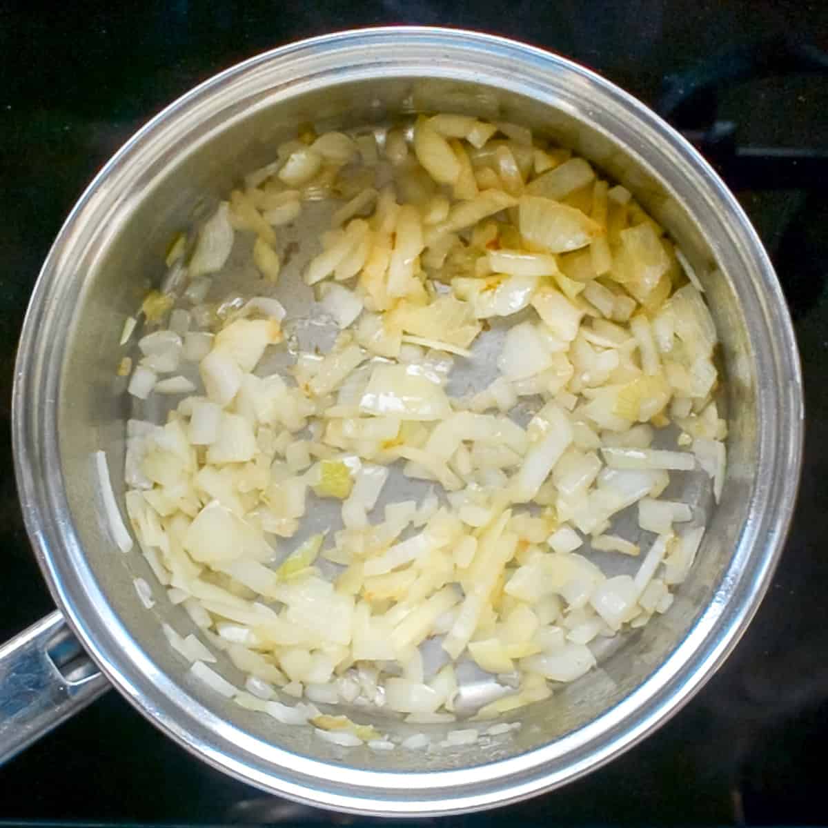 Onions sauteed to a light brown colour in a saucepan.