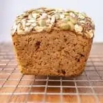A loaf of seeded rye sourdough loaf cooling down on a wire rack.