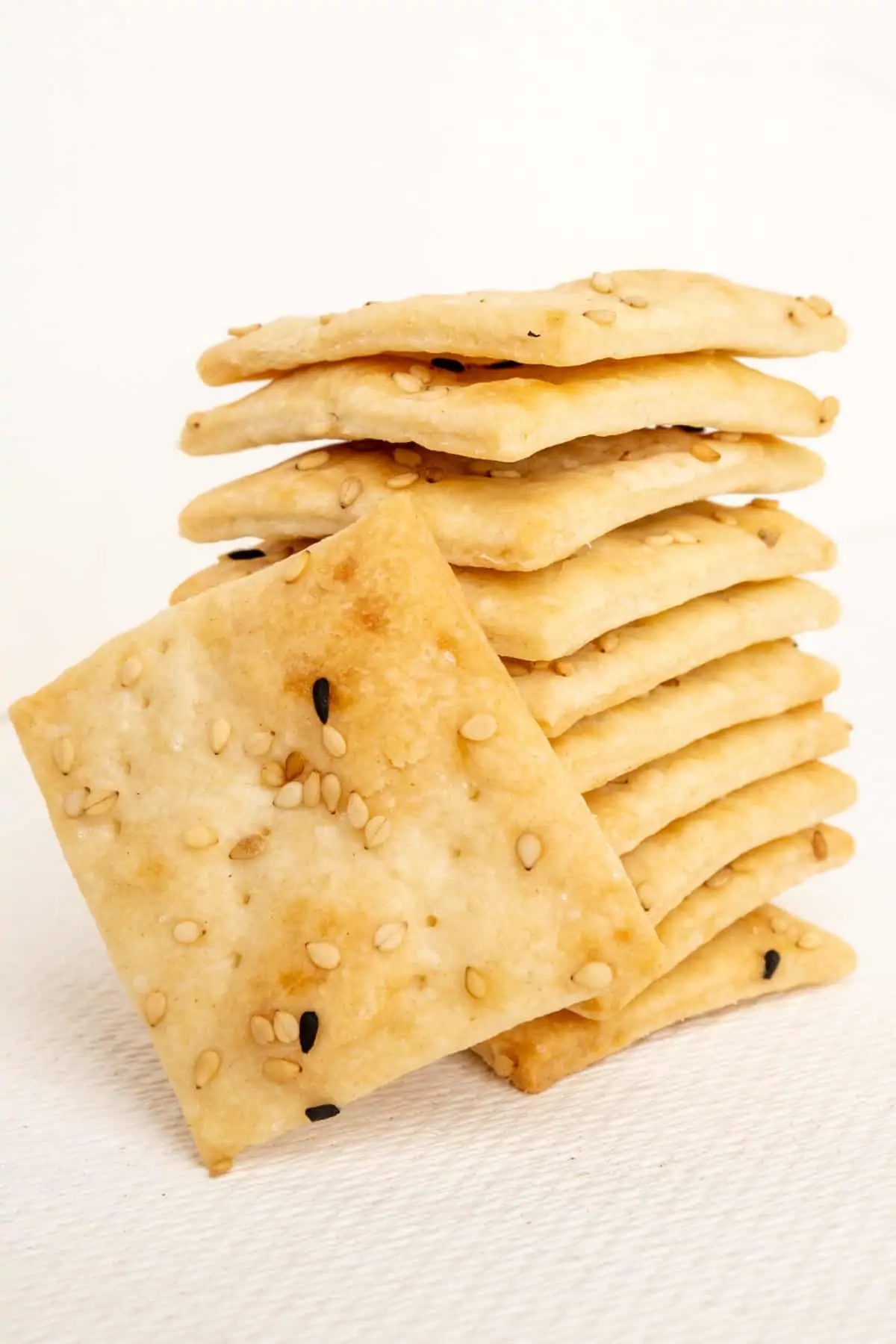 A stack of small sourdough crackers topped with sesame and nigella seeds.