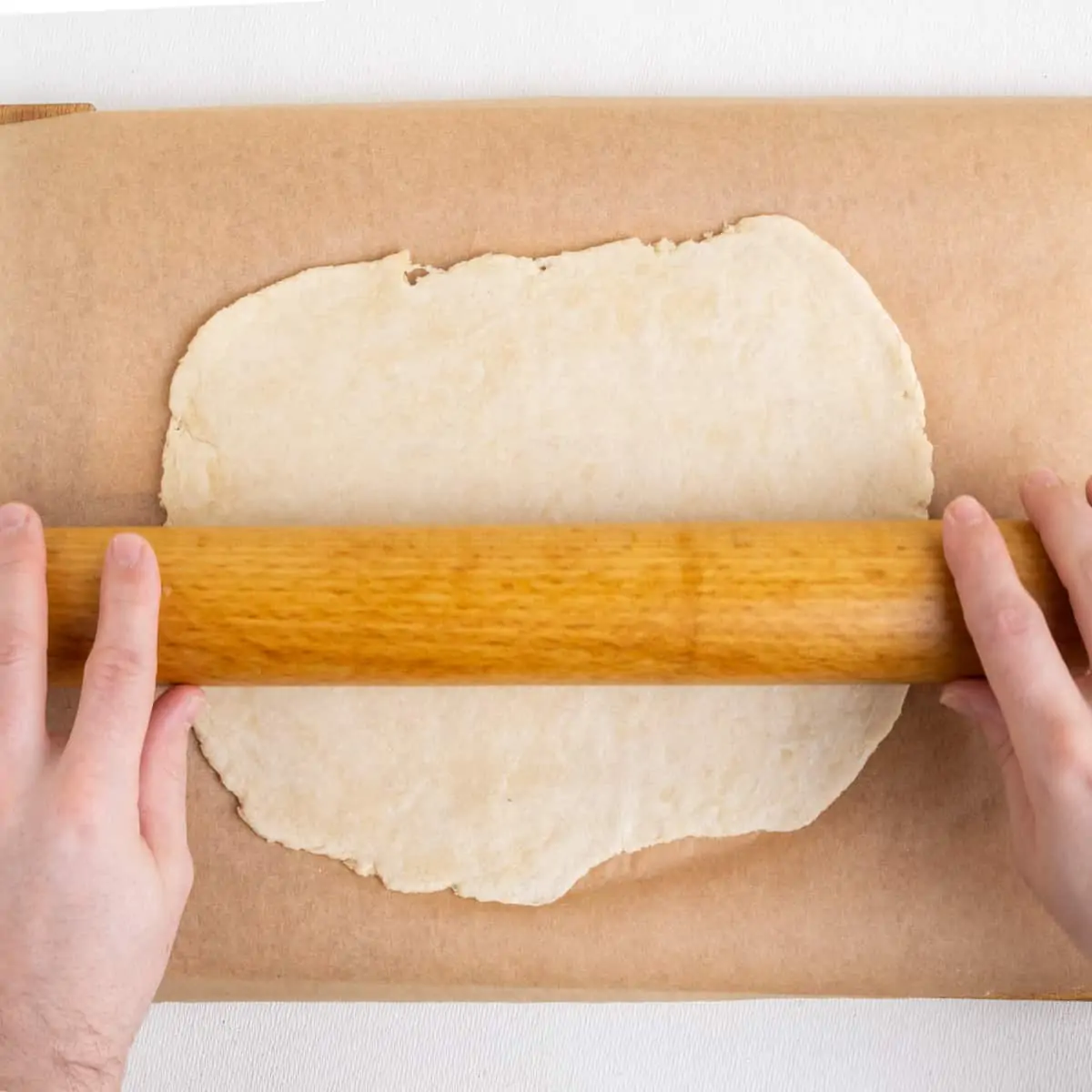 Rolling out the dough on a piece of parchment paper.