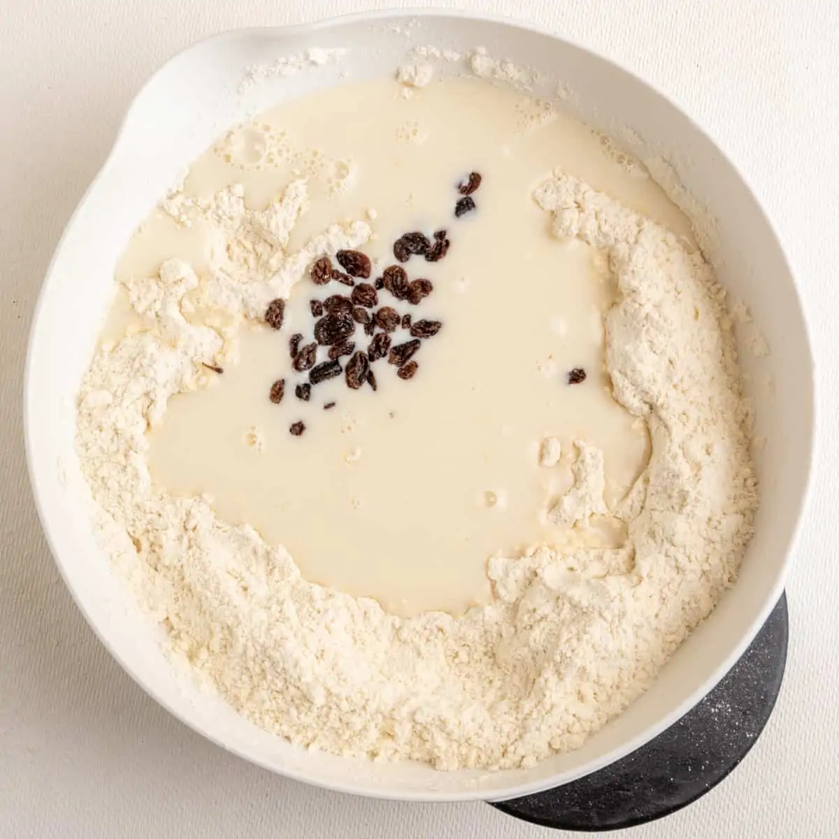Soy milk and raisins are added into the mixing bowl to the other ingredients, and a dough is mixed.