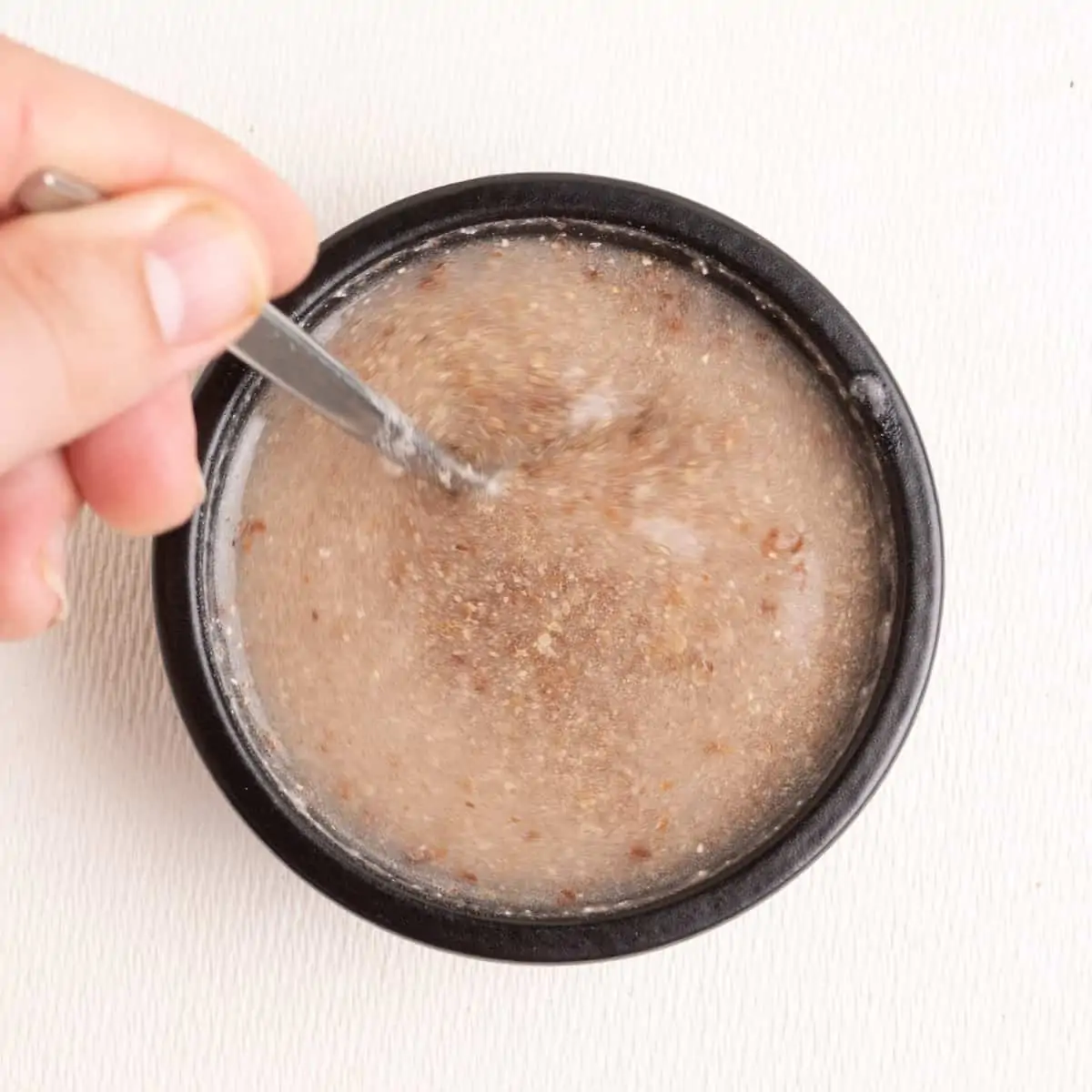 A spoon stirs ground flaxseed and water together.