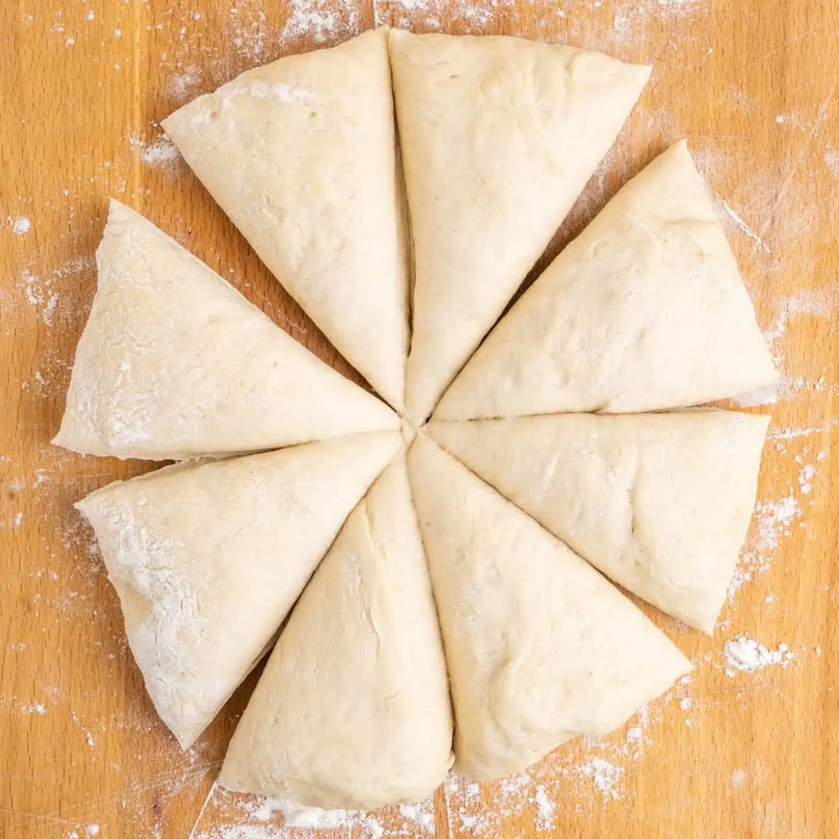 The dough divided into 8 equal parts like cake slices on a floured wooden board.
