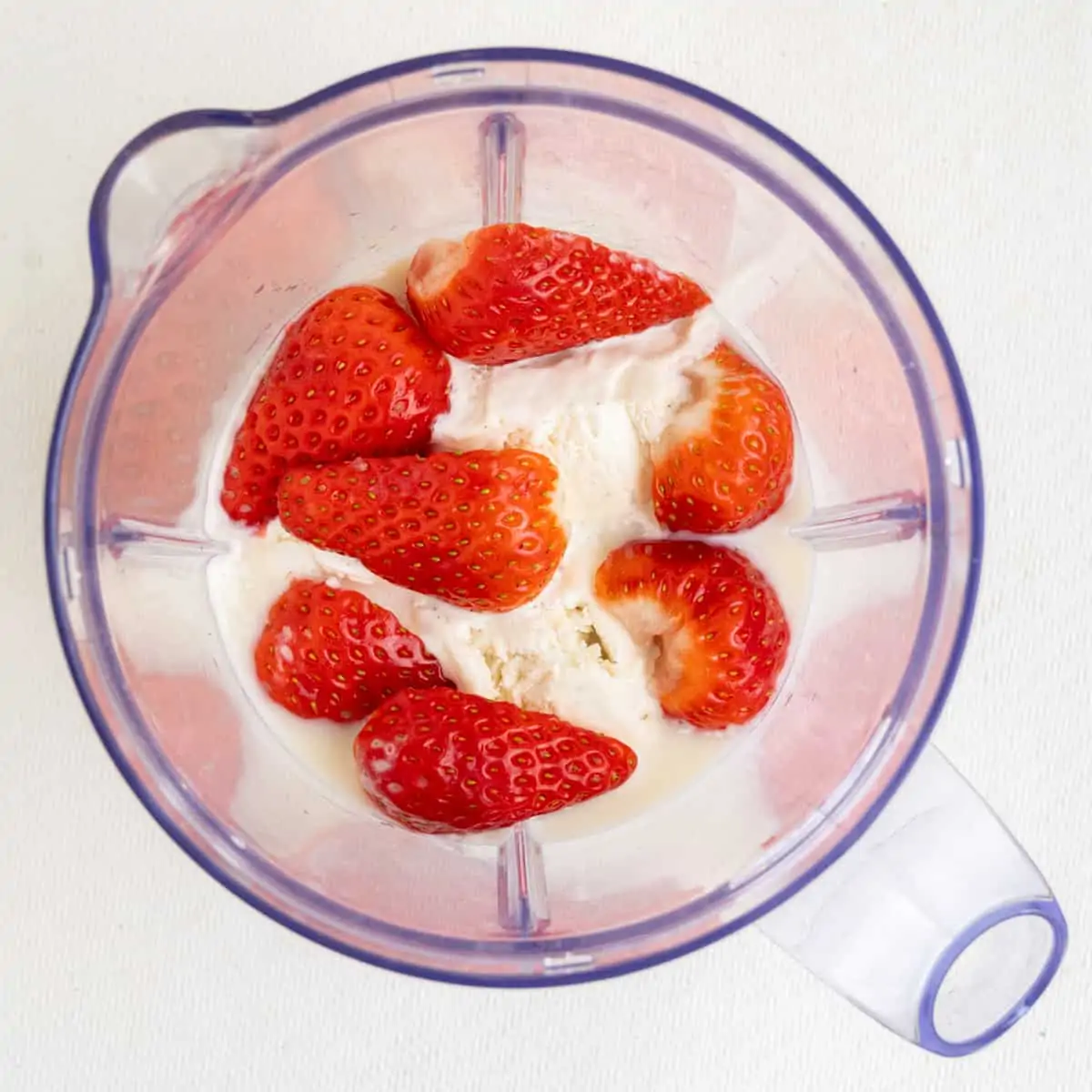 Strawberries, icecream and oat milk in a blender jug.