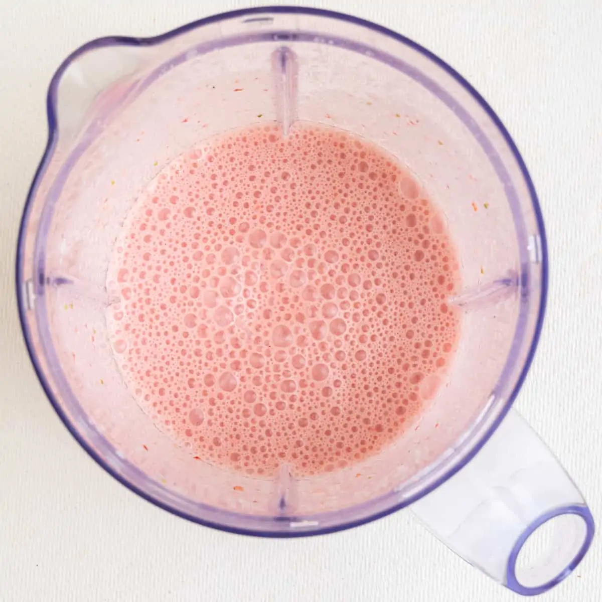 The shake after blending: A bubbly and creamy, pink mixture.