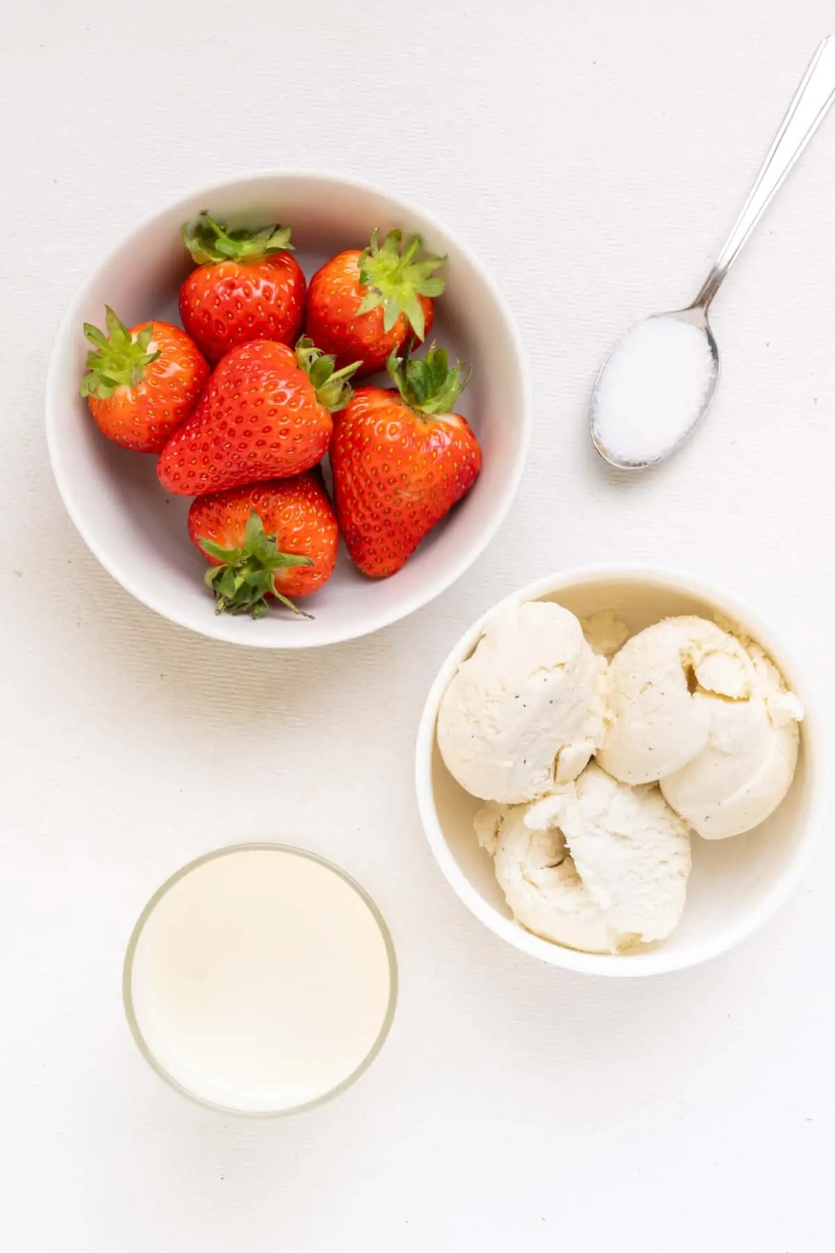 The ingredients for the milkshake: fresh strawberries, plant based vanilla ice cream and oatmilk. A spoonful of sugar is optional.