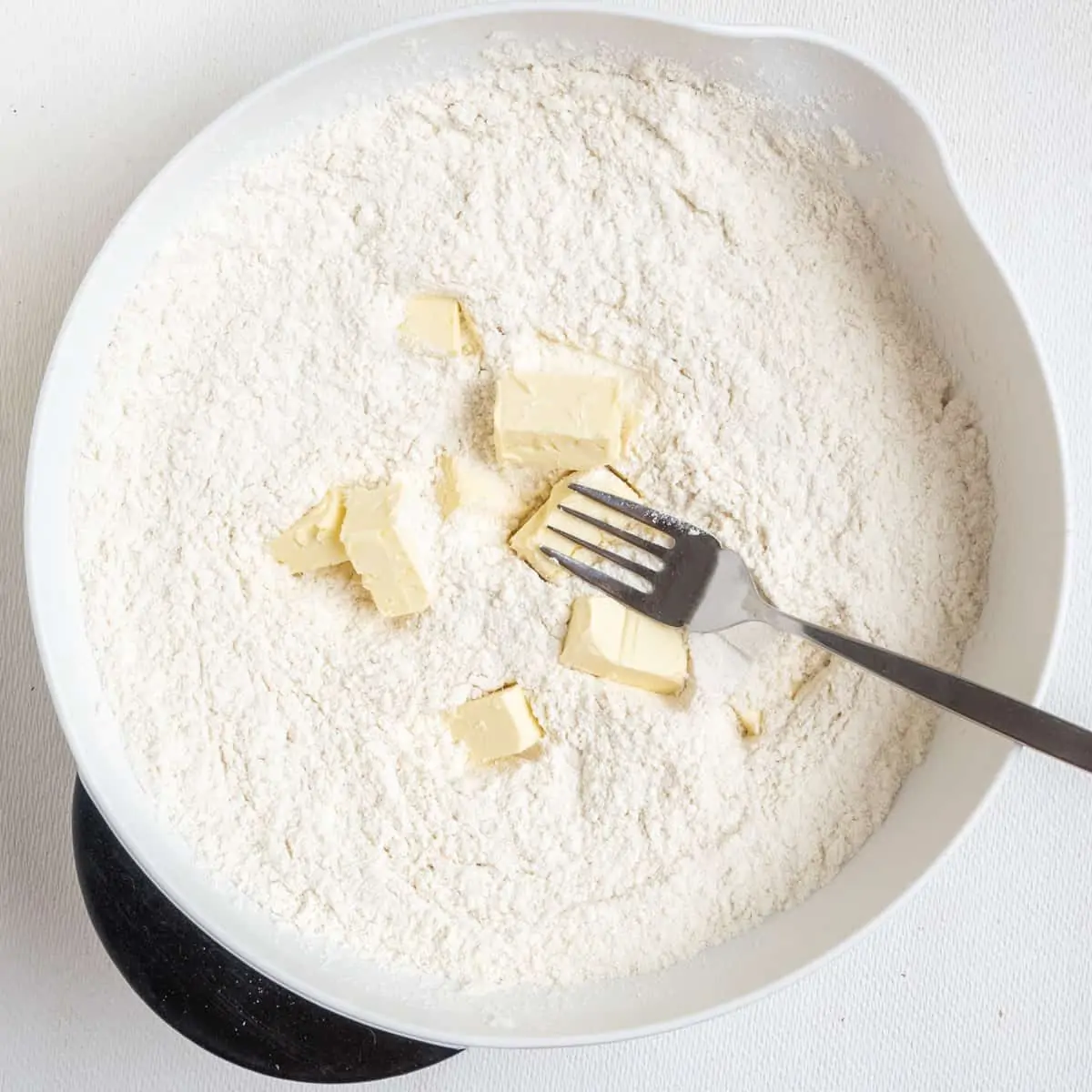 cubes of butter in a dry floury mix of ingredients in a mixing bowl.