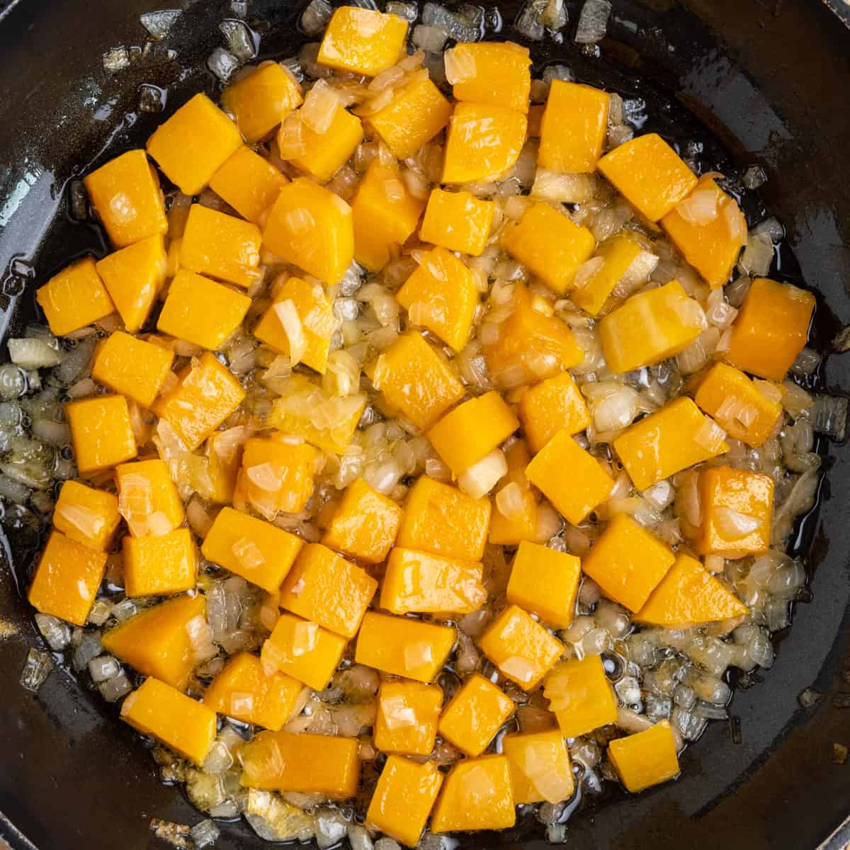 Sauteed butternut squash and onion in a pan.