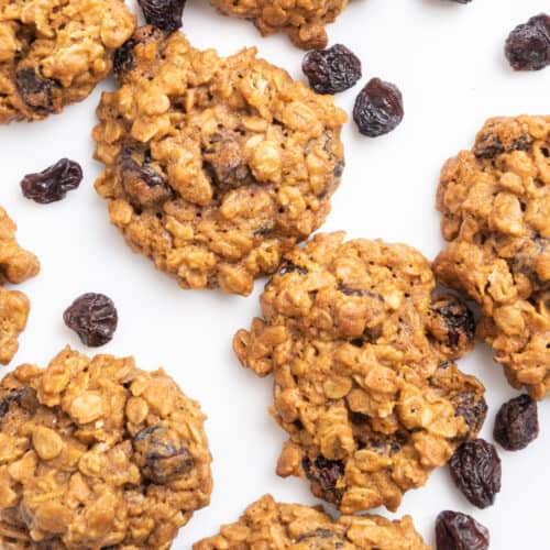 cookies with oats and raisins on a white surface.