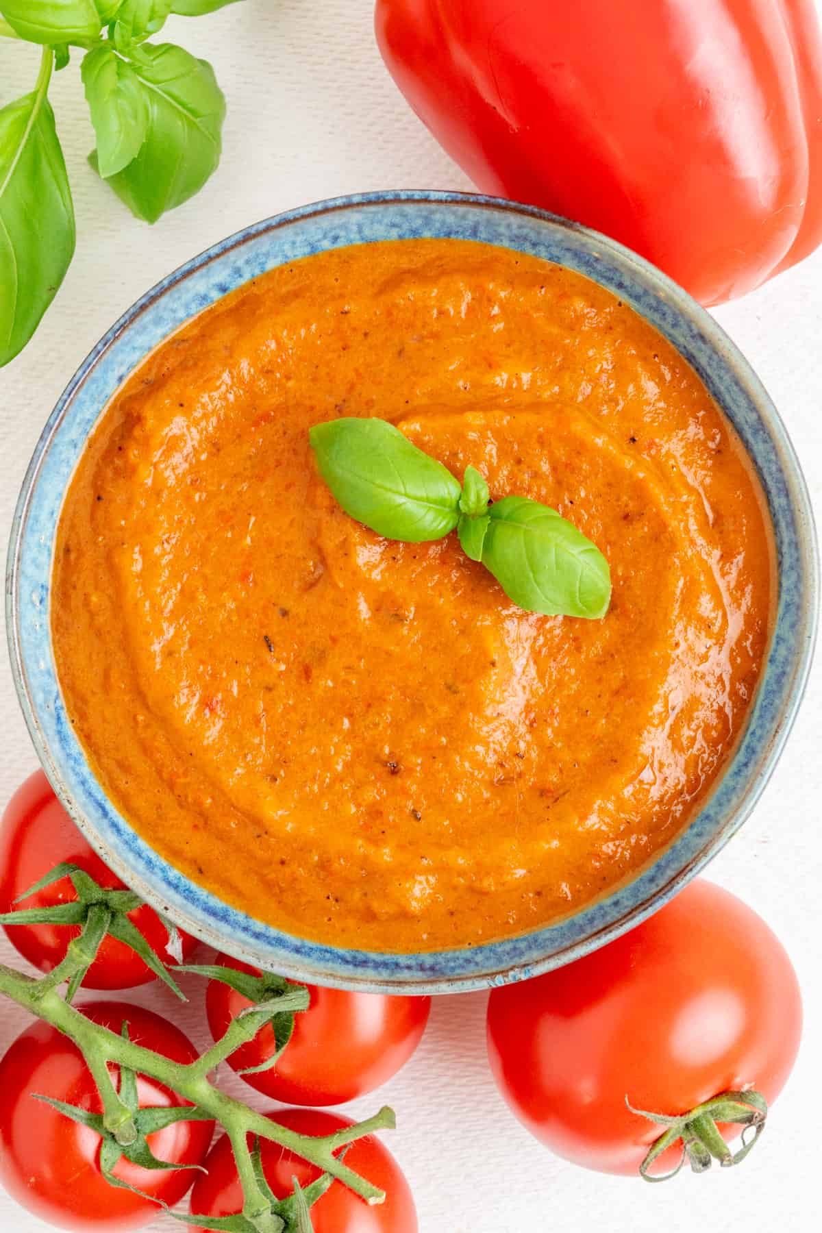 Smooth and thick, orange red sauce in a bowl, topped with fresh basil.