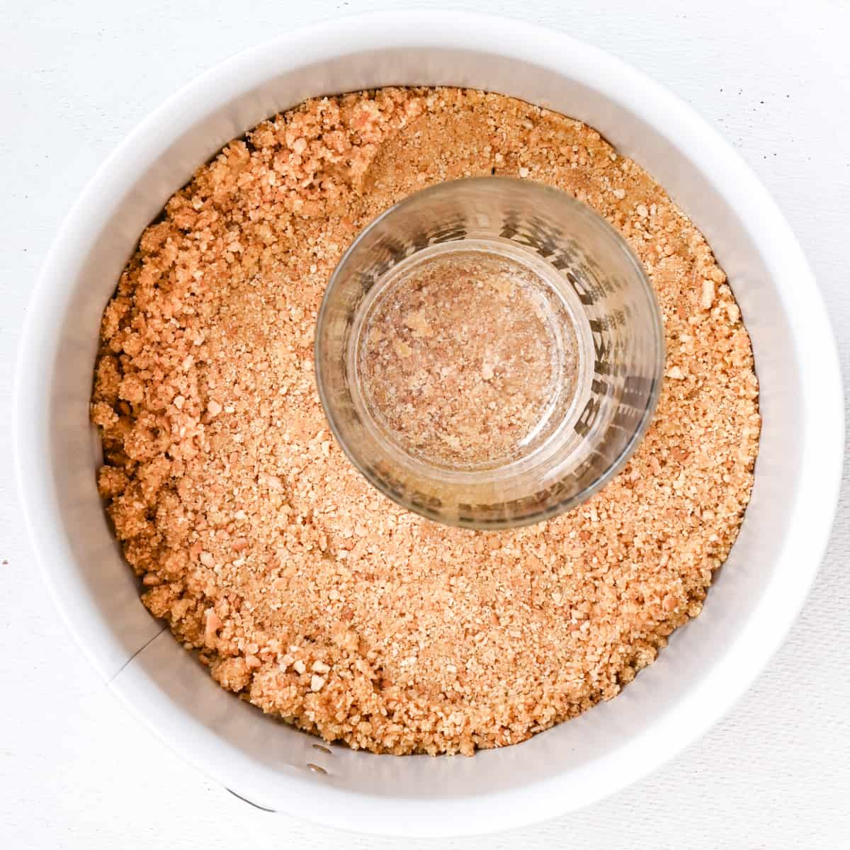 The crumbly tart base is pressed into a cake tin using the flat bottom of a drinking glass.