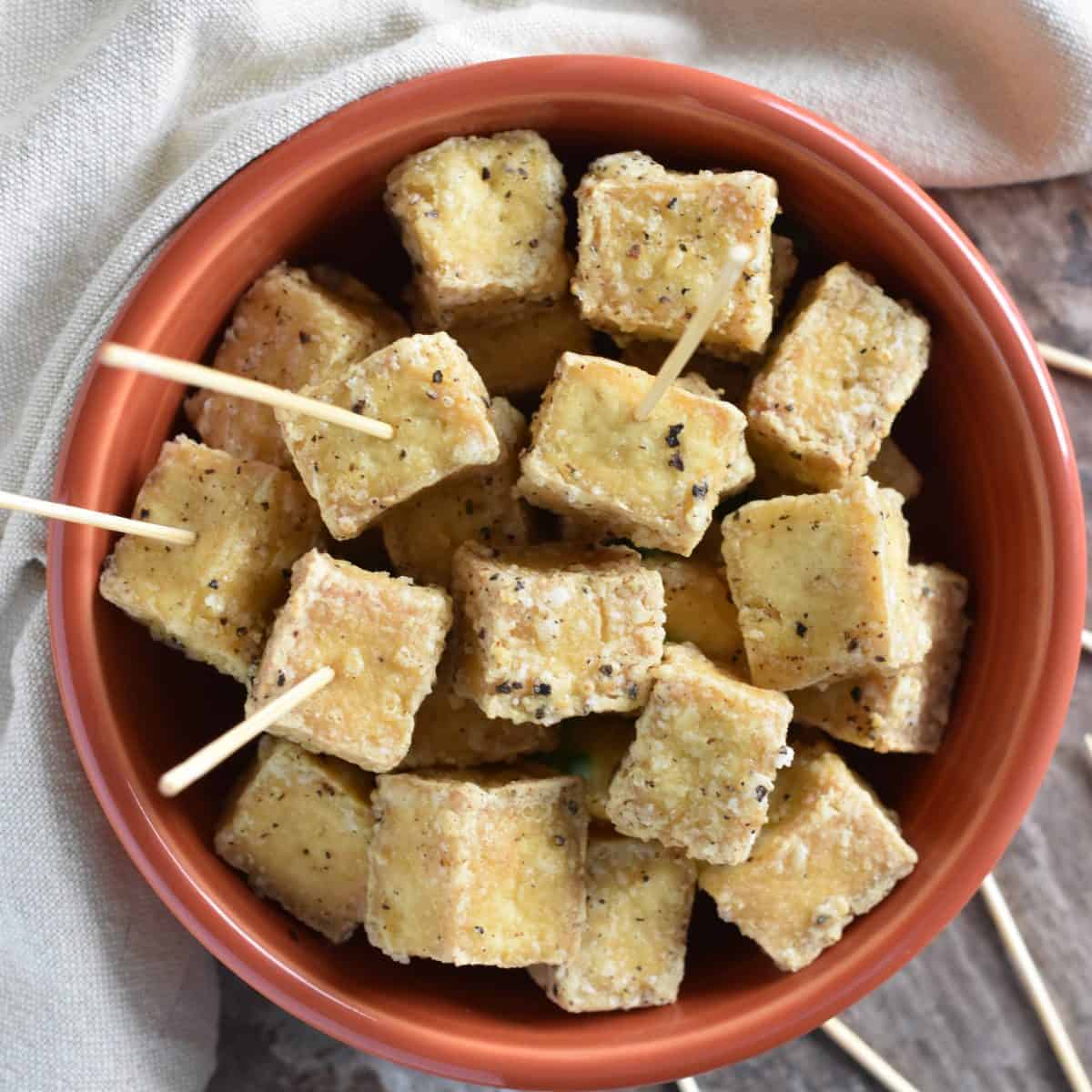 Crispy tofu cubes in a terracota dish.
