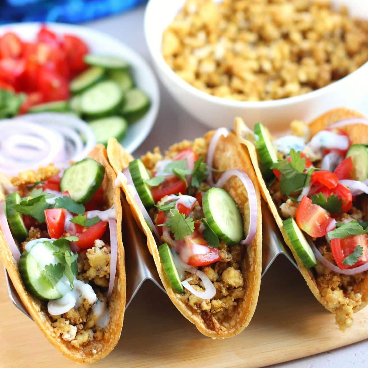 Three vegan tacos on a board.