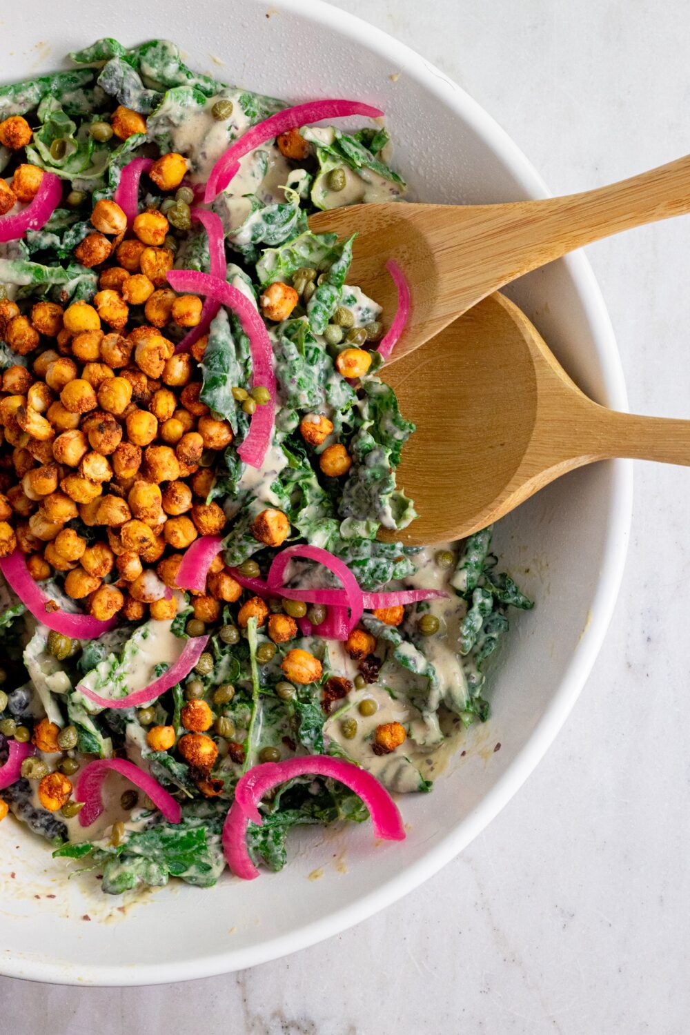 A kale salad topped with chickpeas and pickled onions. 