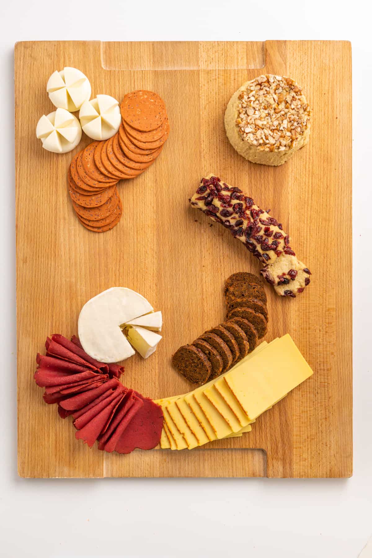 Vegan cheeses and ready-to-eat meat alternatives arranged on a wooden board.
