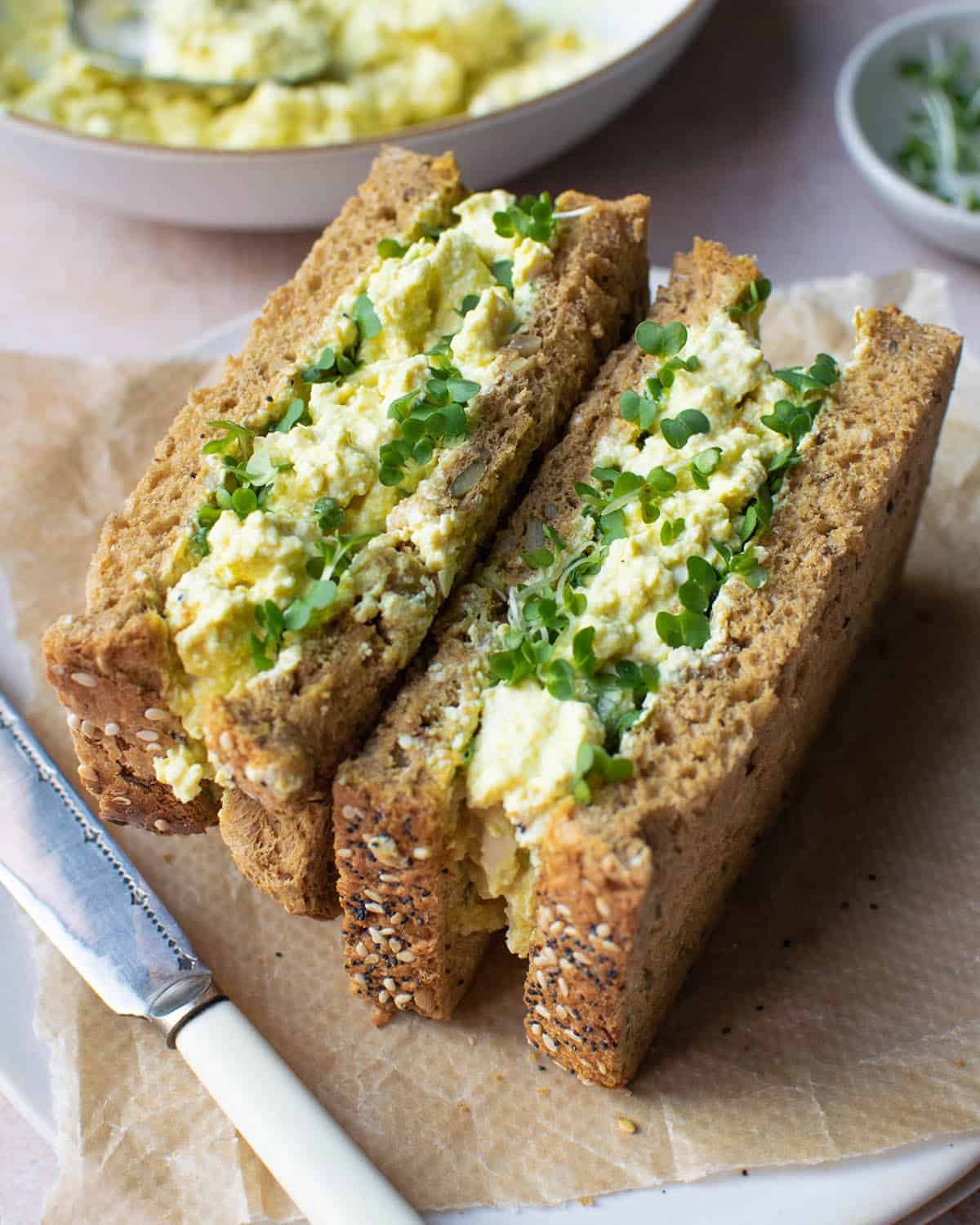 Two vegan egg mayo sandwishes on a plate.