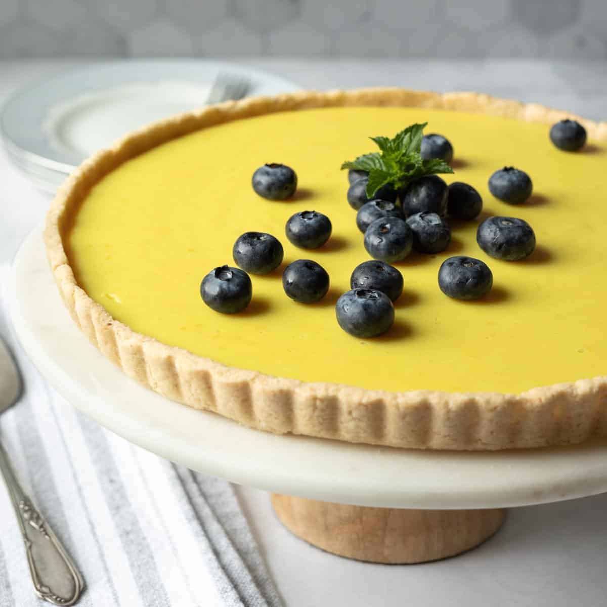 A lemon tart on a cake stand.