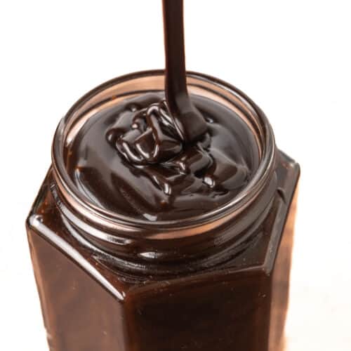 The fudge sauce is poured into a jar, the folds from the pour only disappearing after a while becaue of the sauce's thick texture.