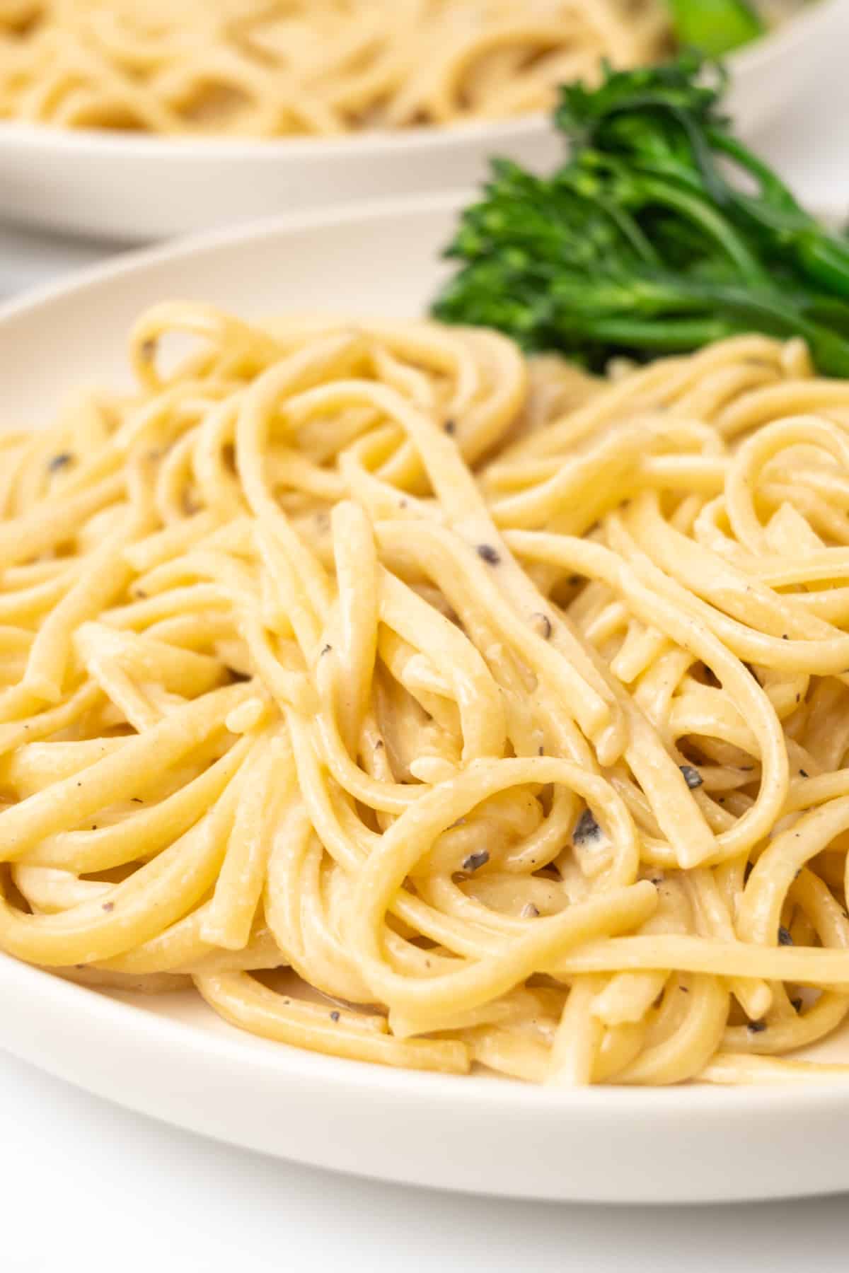 A plate of pasta in a creamy sauce of tahini with crushed black pepper.
