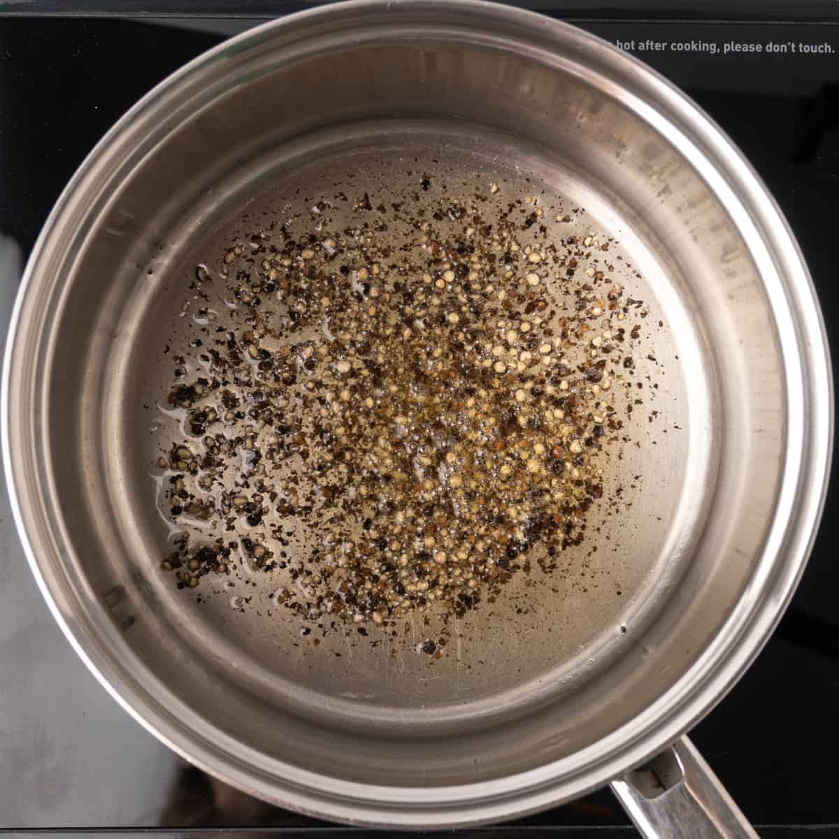 Crushed pepper sizzling in olive oil in a saucepan.
