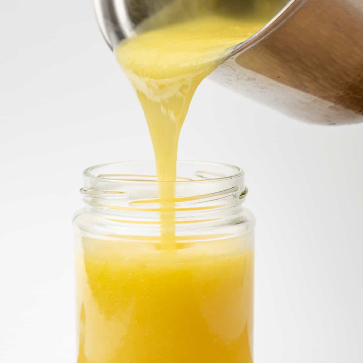 Ζεστό τυρόπηγμα λεμονιού χύνεται από μια κατσαρόλα σε ένα βάζο.