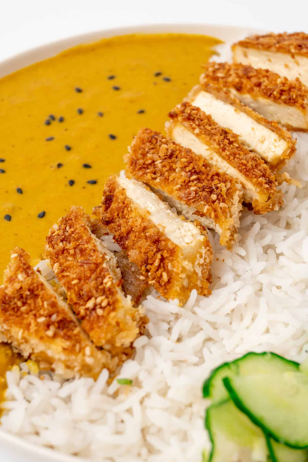 Slices of tofu cutlet on top of rice, with a Japanese curry sauce.