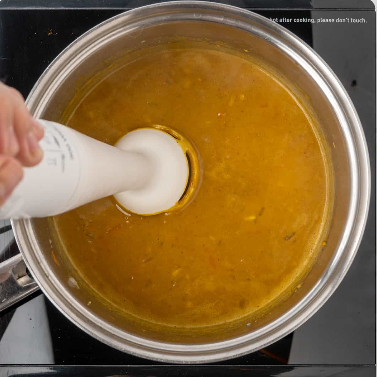 Blending the curry sauce with an immersion blender.