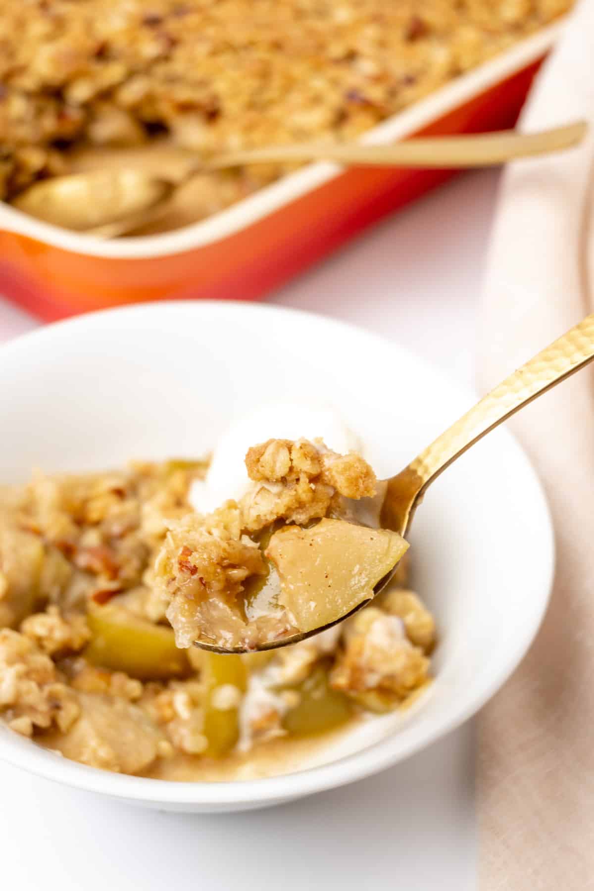Juicy, tender apple pieces with crispy oat topping on a spoon.