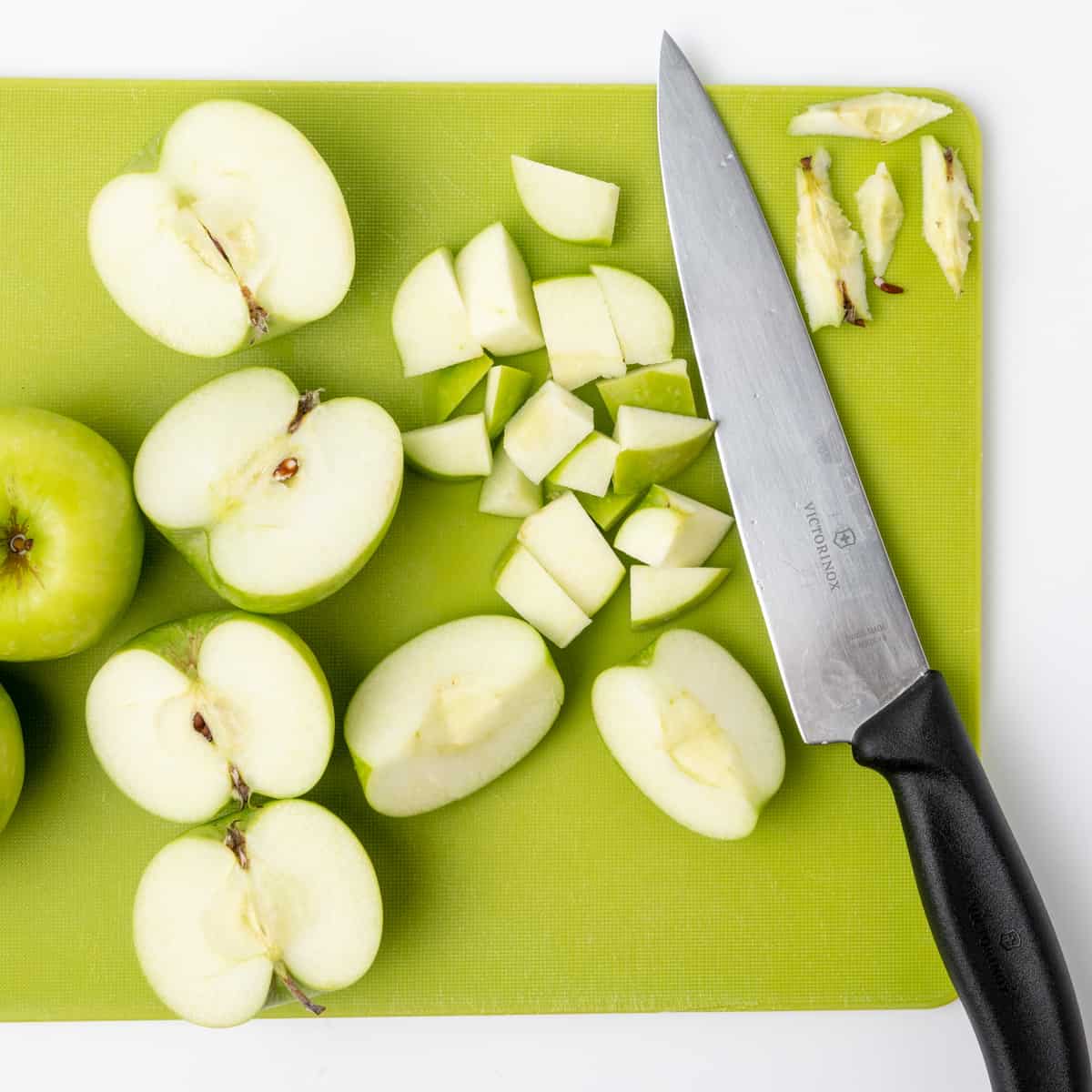 Coring and chopping apples on a green board.