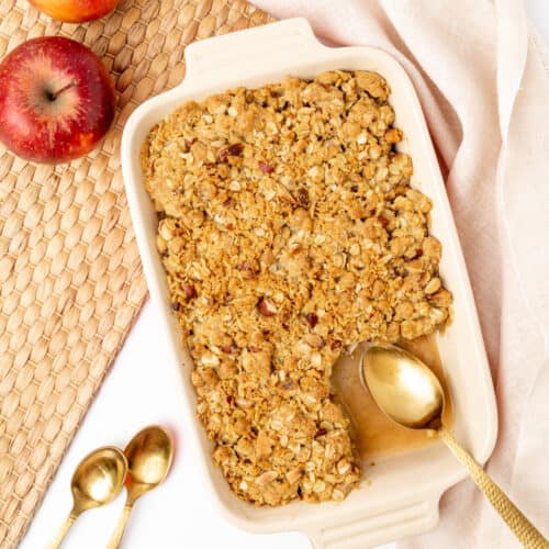 Apple crisp in a baking dish, with one portion already served.