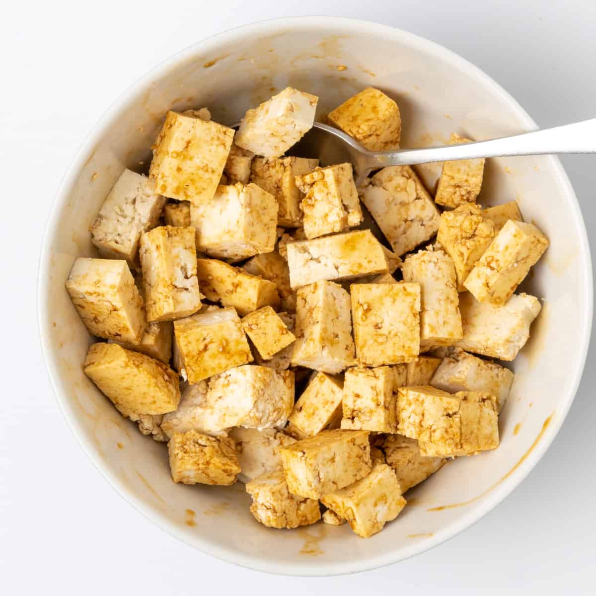 Cubes of tofu covered in soy sauce in a bowl.