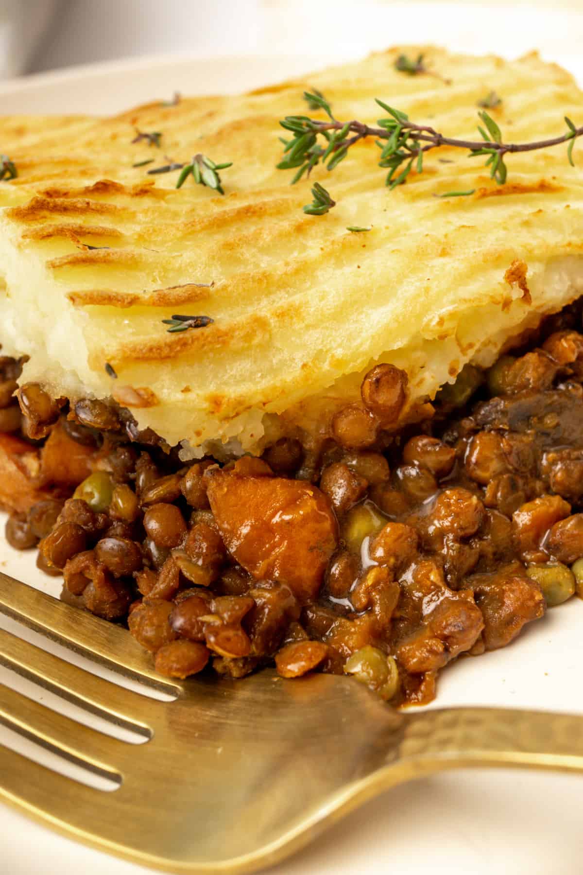 A close up of a slice of shepherd's pie and its lentil and vegetable filling.