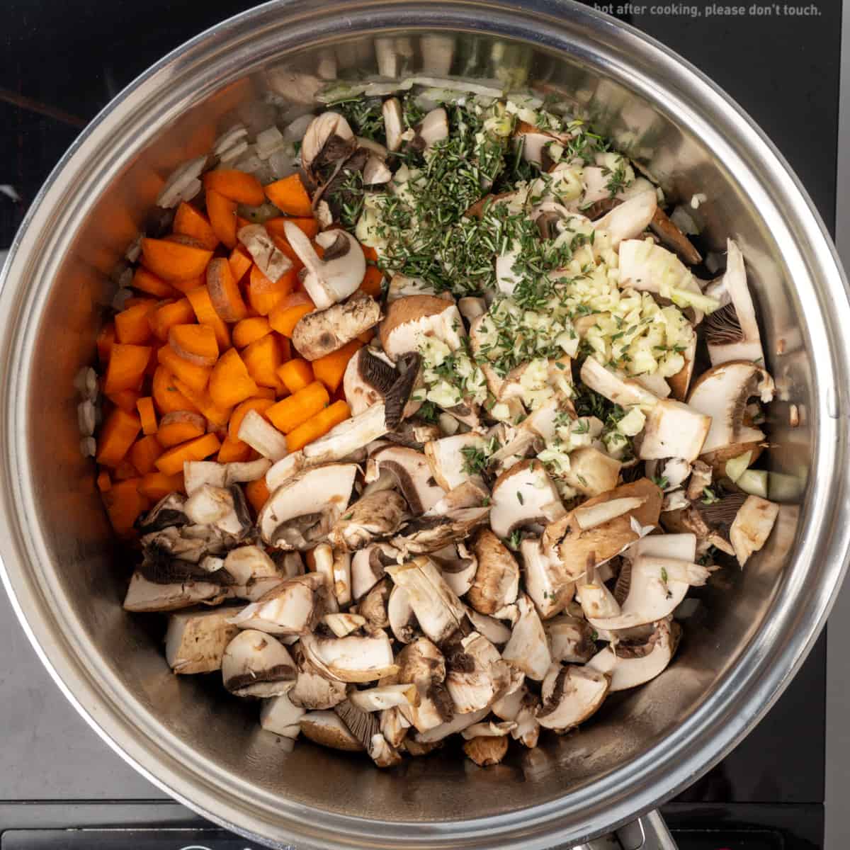 Diced carrots and mushrooms with minced garlic and herbs in a saucepan.