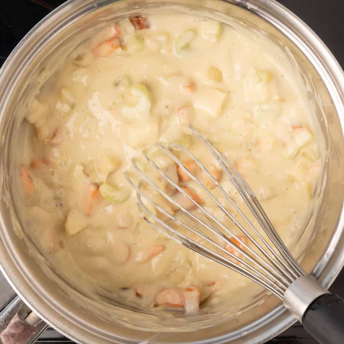 A thick creamy sauce with diced vegetables in a saucepan.
