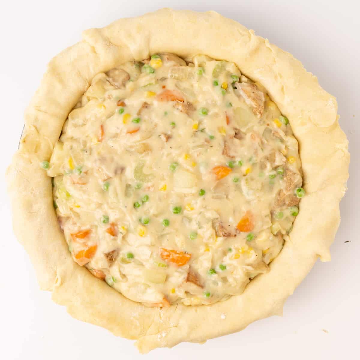 A pastry shell filled with a creamy vegan pot pie filling in a pie dish.