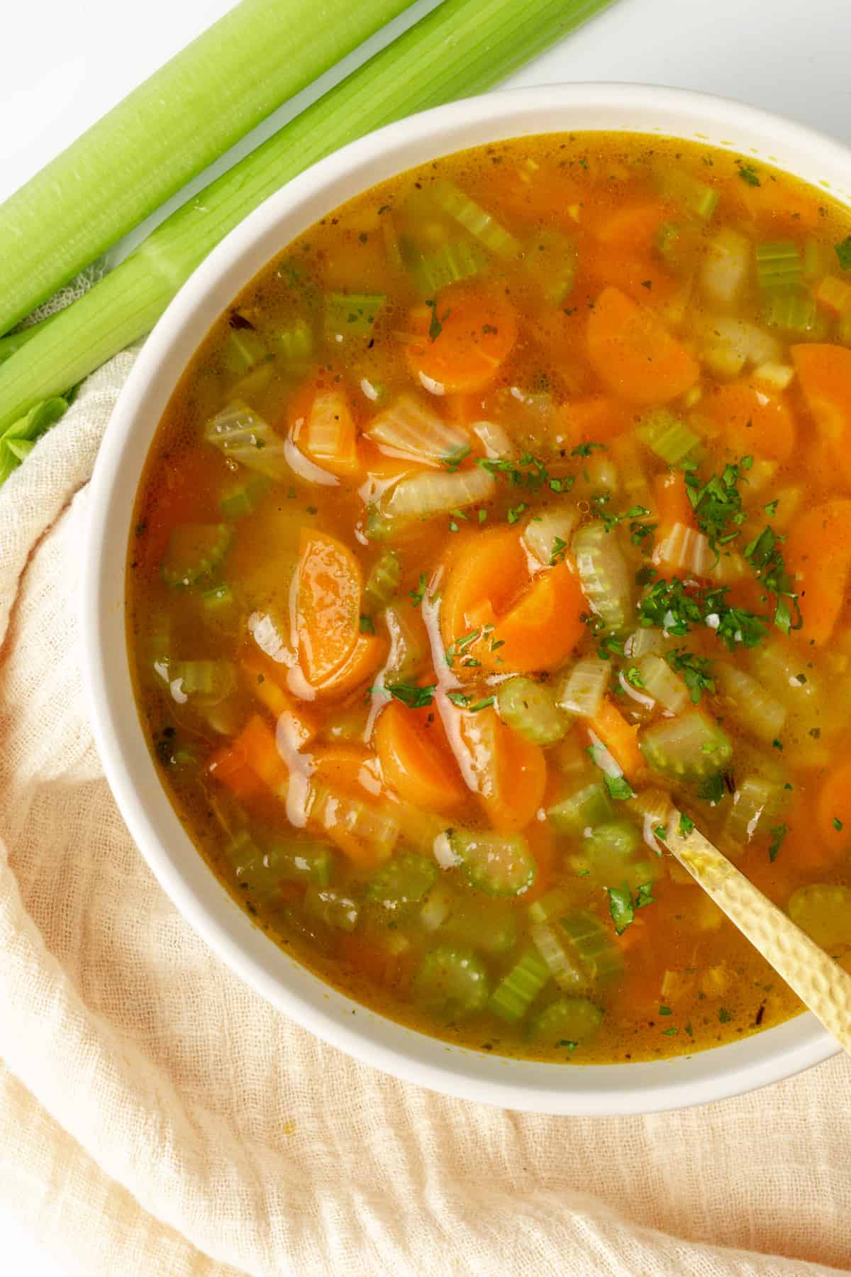 A bowl of soup with pieces of carrots and celery.