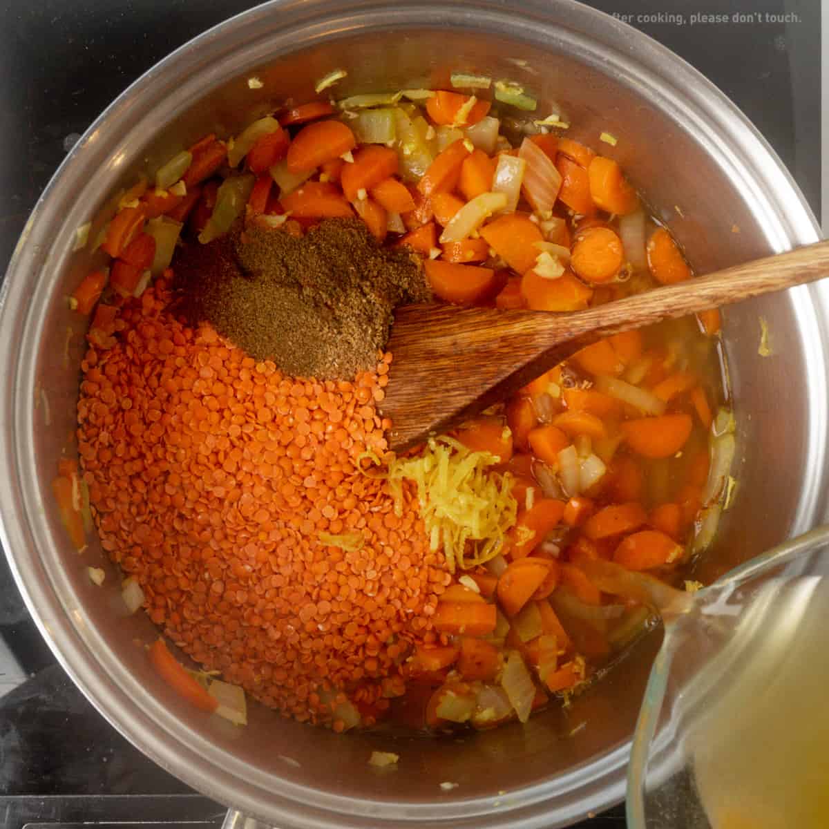 Red lentils, ground spices, lemon zest and vegetable broth are added to a saucepan containing chopped carrots and lentils.