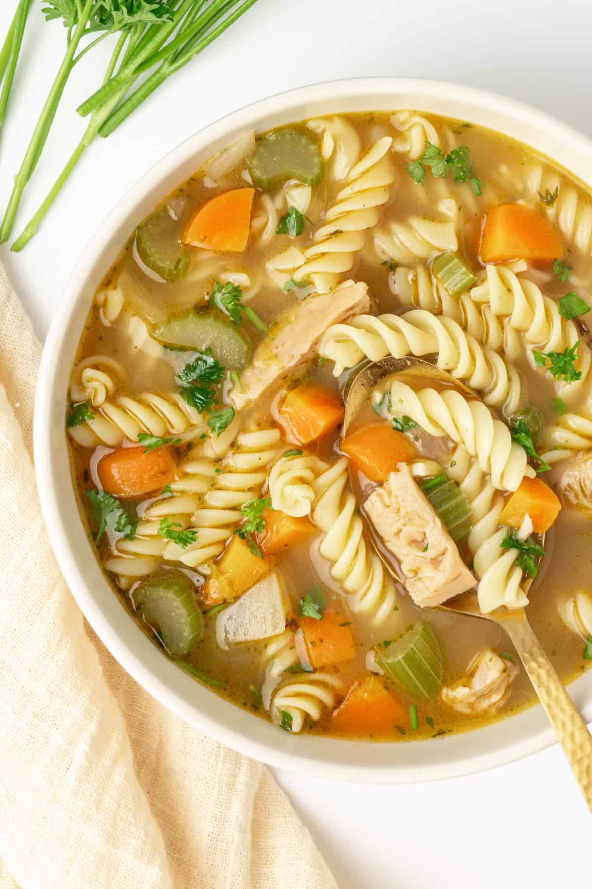 A bowl of vegan chicken noodle soup with a spoon.