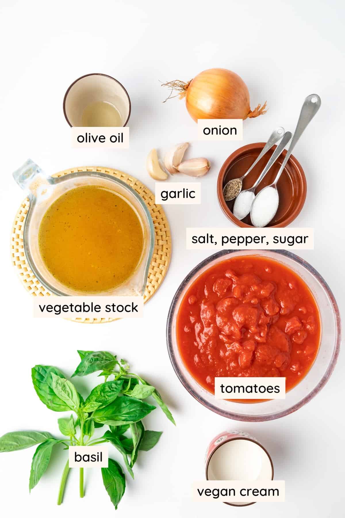 Ingredients for tomato soup: oil, onion, garlic, vegetable stock, chopped tomatoes, basil and vegan cream.