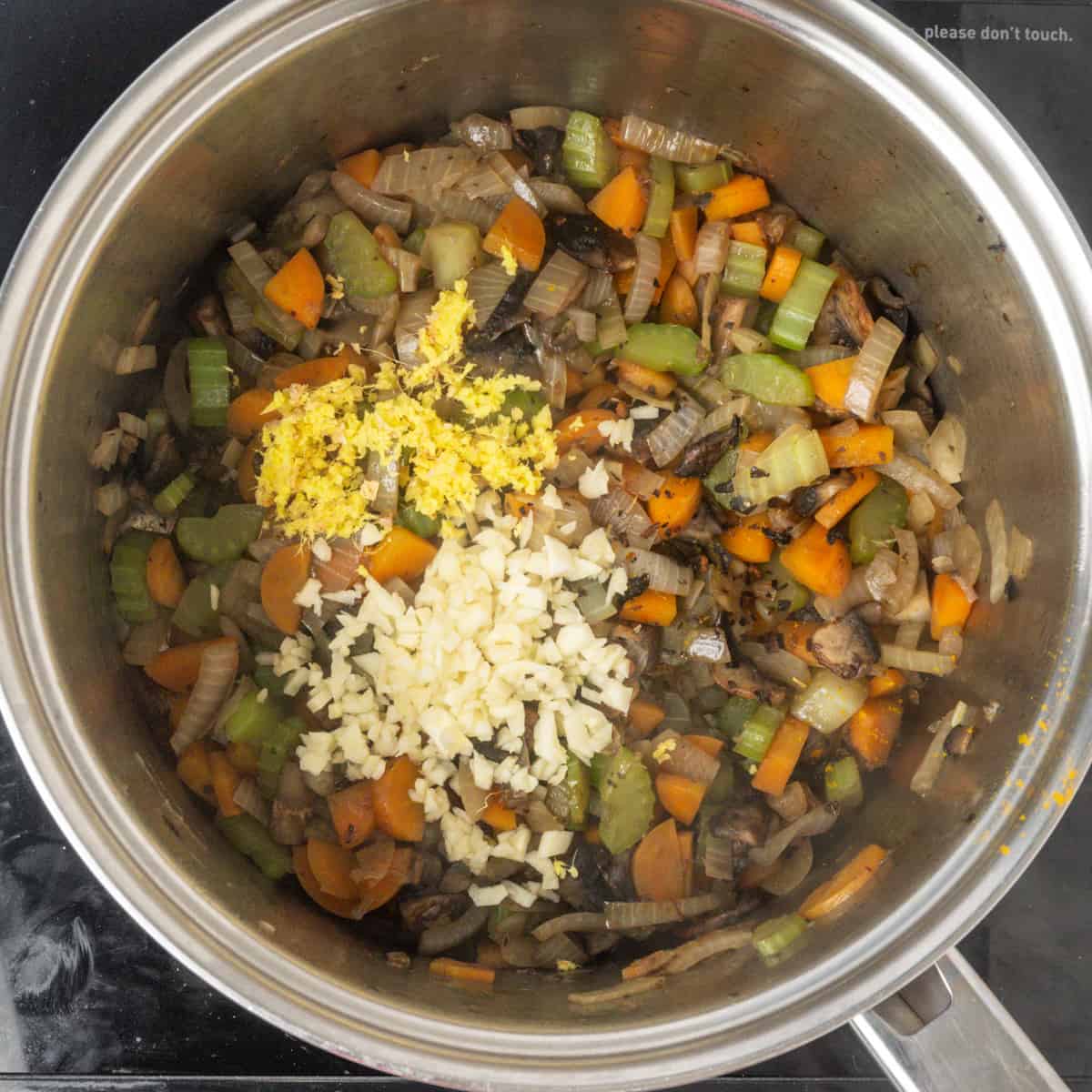 Σοταρισμένα λαχανικά σε ένα τηγάνι με σκόρδο και τζίντζερ από πάνω.