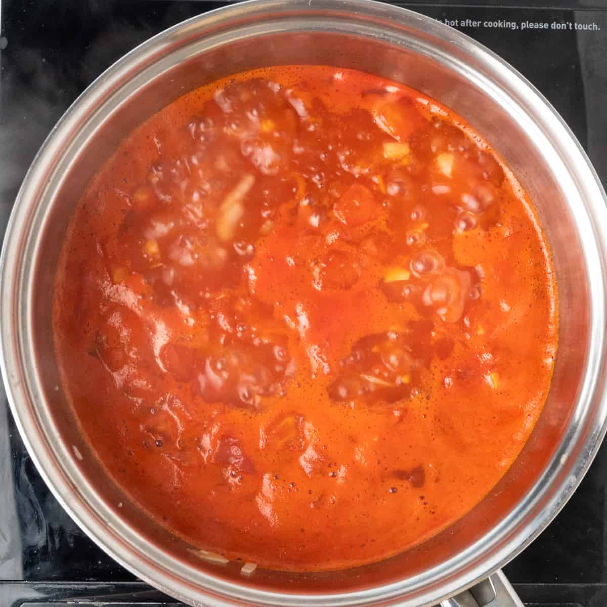 Simmering tomatoes and onions in a pot.