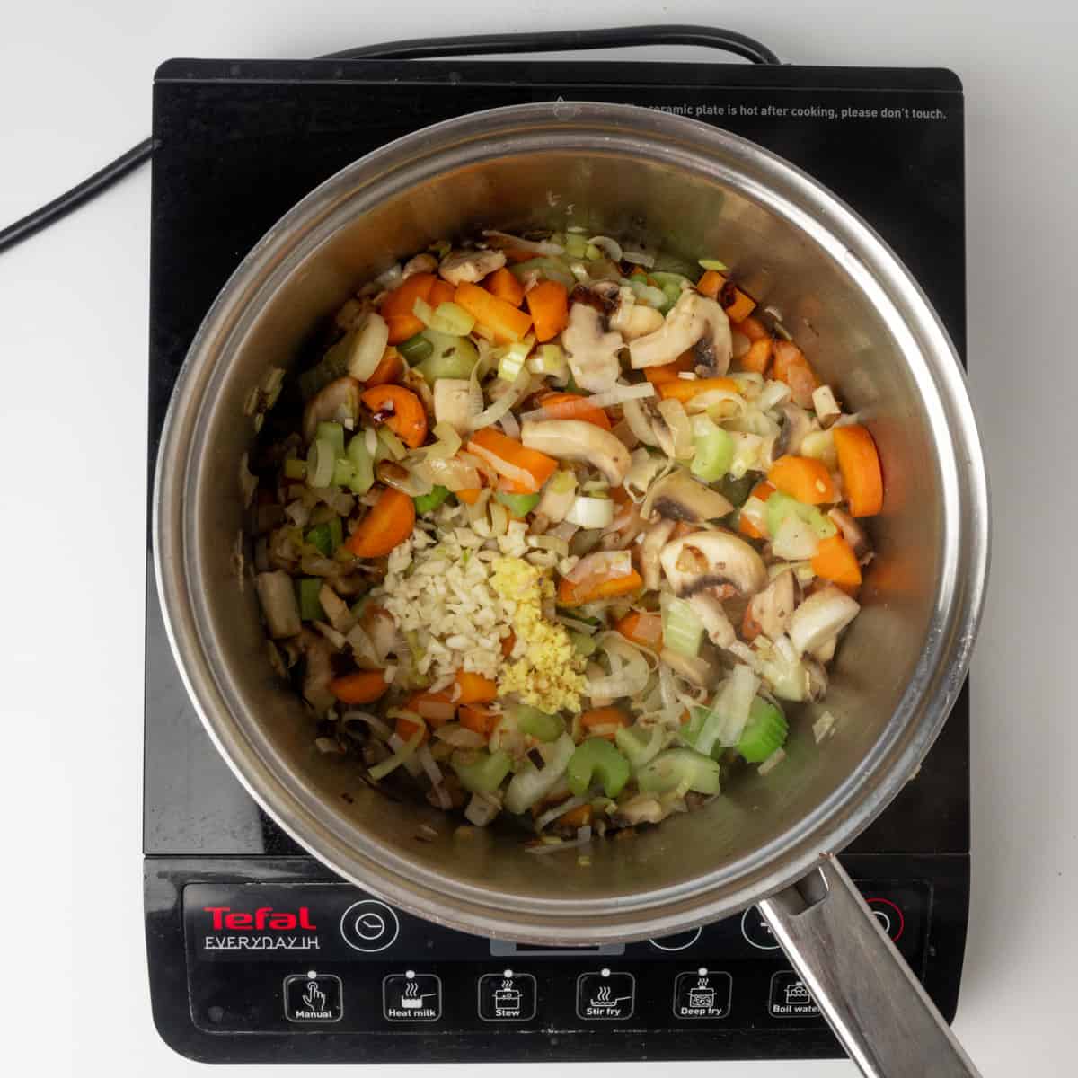 Adding garlic and ginger to sauteed veggies in a pan.