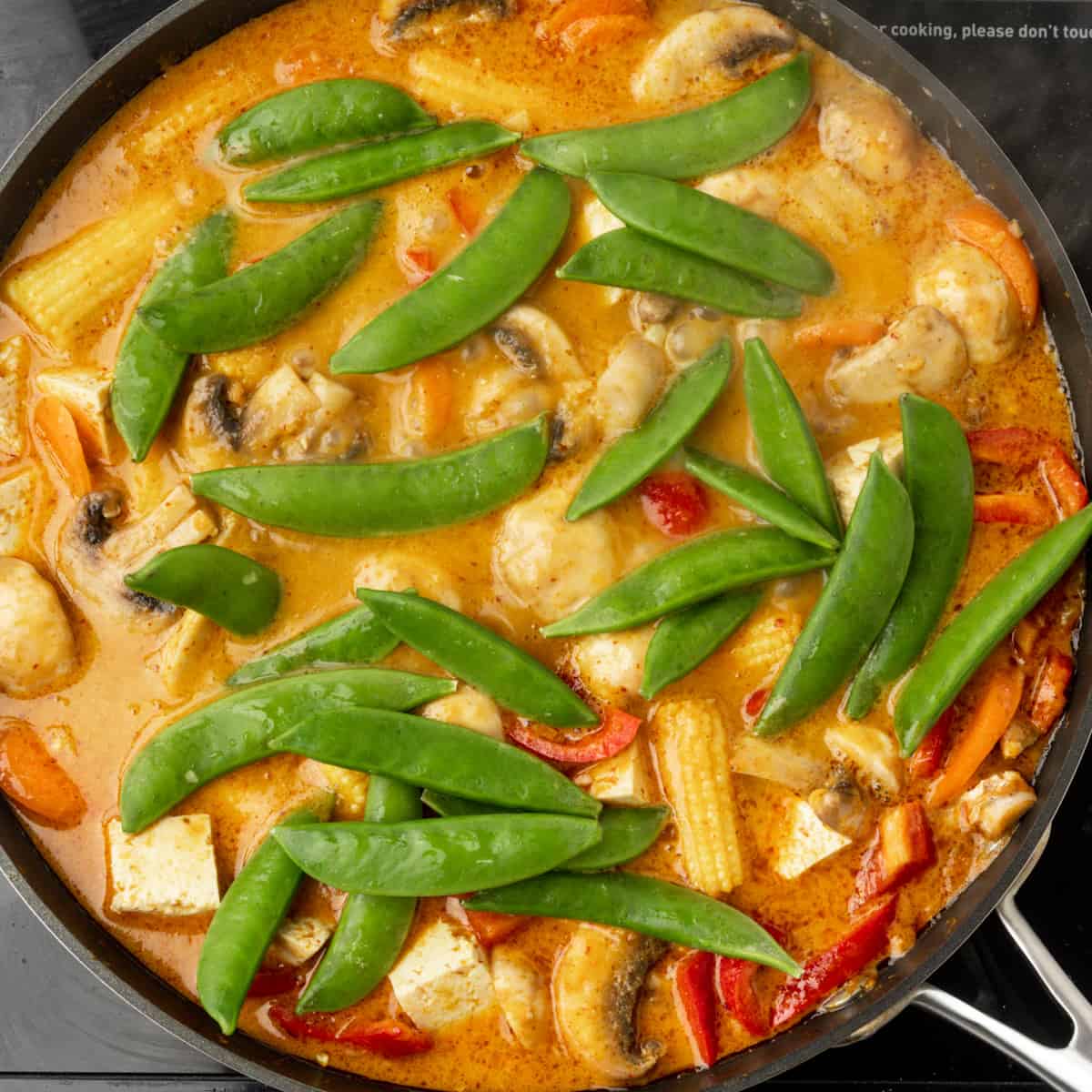 Adding snap peas to Thai red curry.