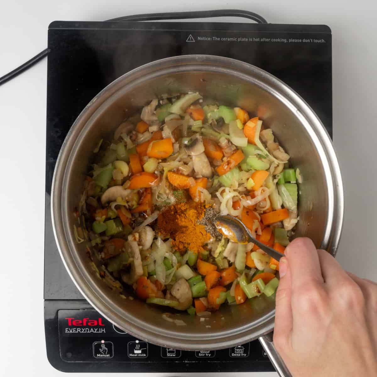 Adding spices to sauteed veggies in a pot.