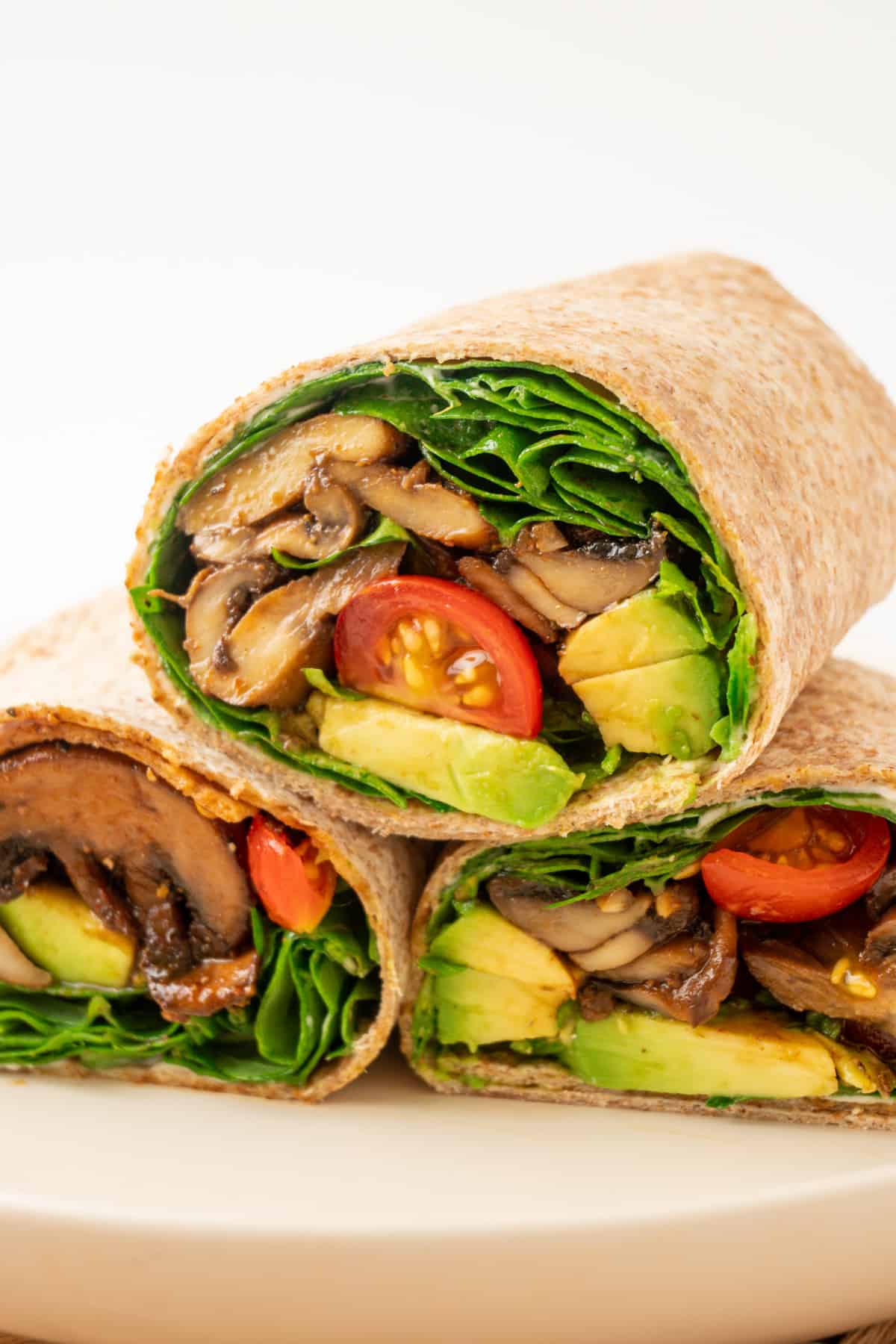 A stack of three mushroom, spinach, tomato and avocado wraps.