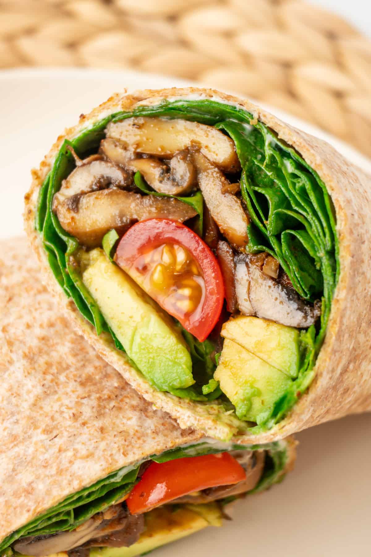 A wholemeal wrap cut in half, filled with juicy mushrooms and salad.