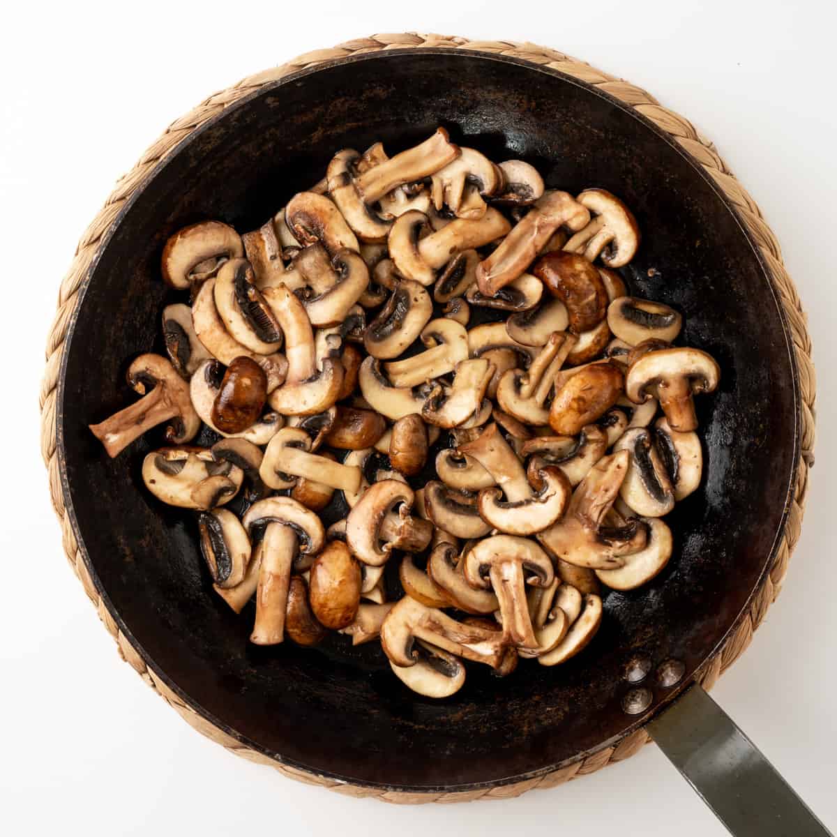 A large skillet with sliced mushrooms.